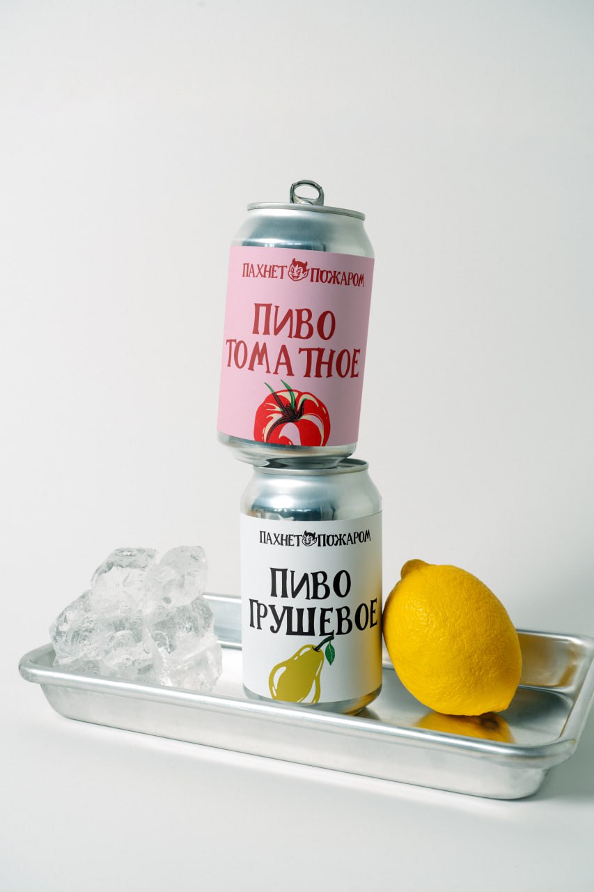Две алюминиевые банки пива на металлическом подносе со льдом и лимоном